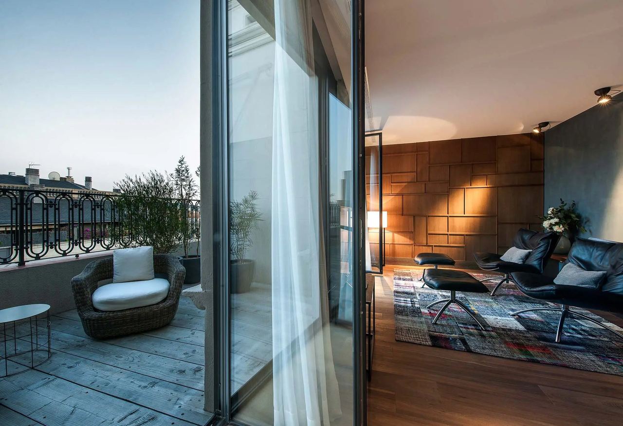 A suite at Alma Barcelona, leather lounge chairs and a timber wall opening onto a private terrace