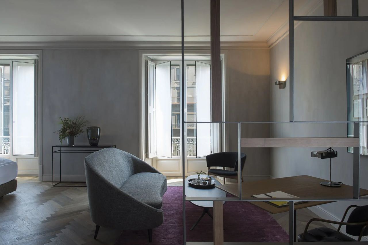 A high-ceilinged room at Alma Barcelona with tall Eixample windows and a herringbone floor