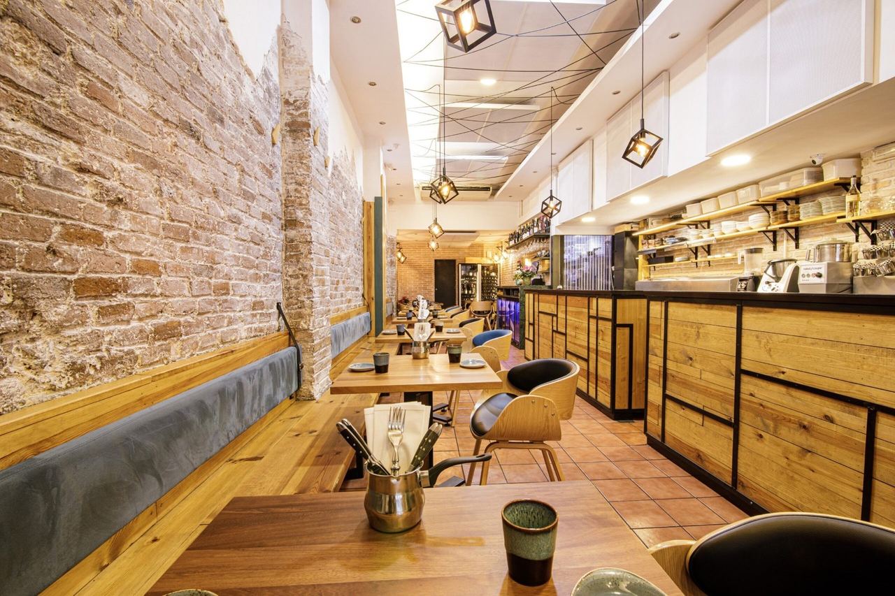 The narrow dining room at Cruix, a bare-brick wall and banquette facing a timber bar