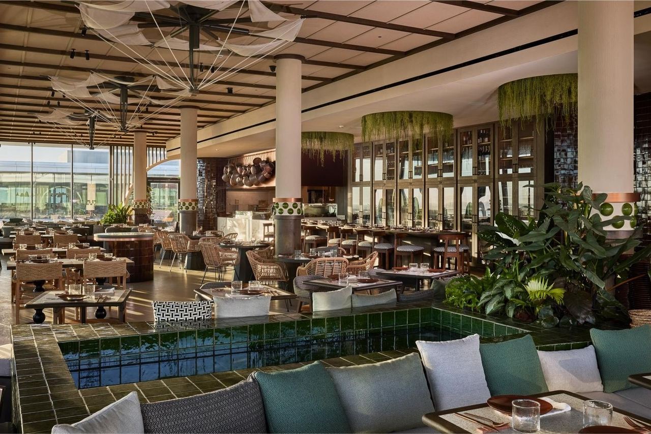The terrace dining room at Eldelmar – Hermanos Torres, sofas round a green-tiled pool under sail-cloth lamps