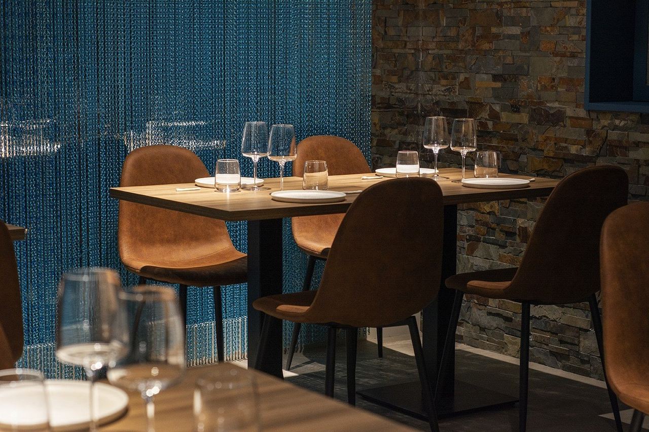 Tables set before a shimmering blue bead curtain and a stone wall at Fishølogy