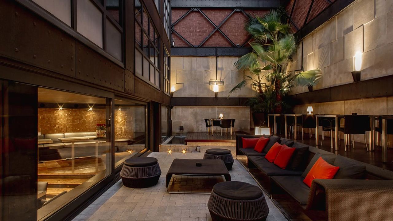 The lantern-lit inner patio lounge at Granados 83, with red cushions under brick and steel