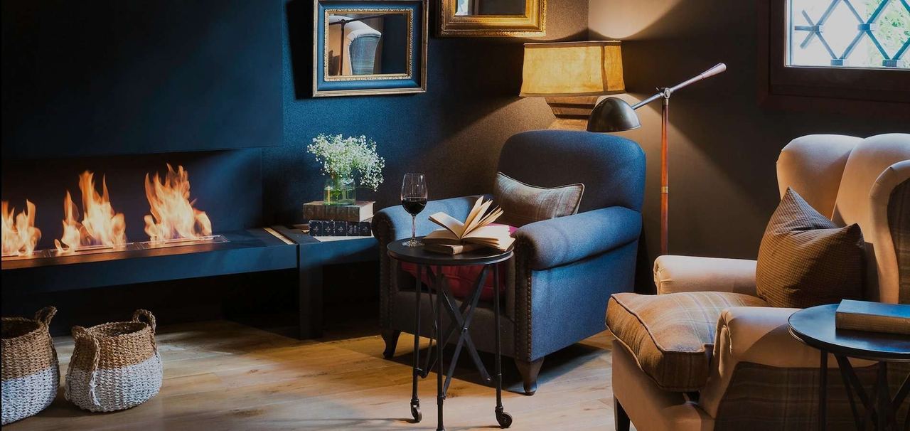 The sitting room at Primero Primera, armchairs and a book by a long open fire