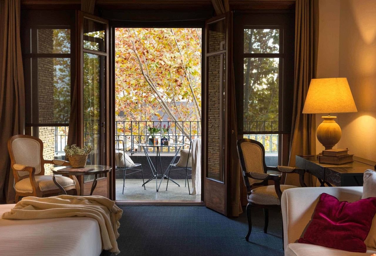 A bedroom at Primero Primera opening onto a balcony among autumn plane trees
