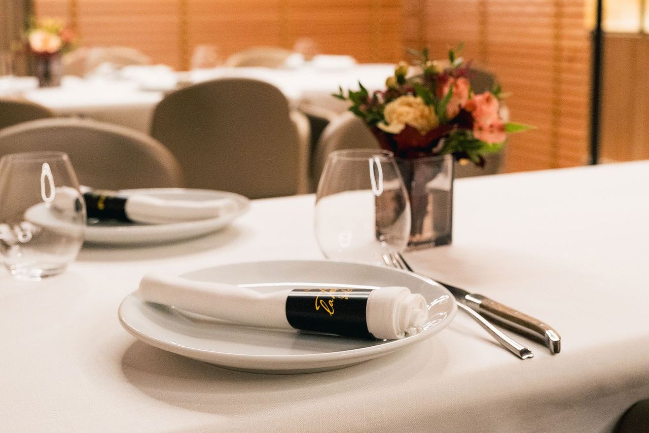 A table laid with white linen and flowers in the dining room at La Taverna del Clínic